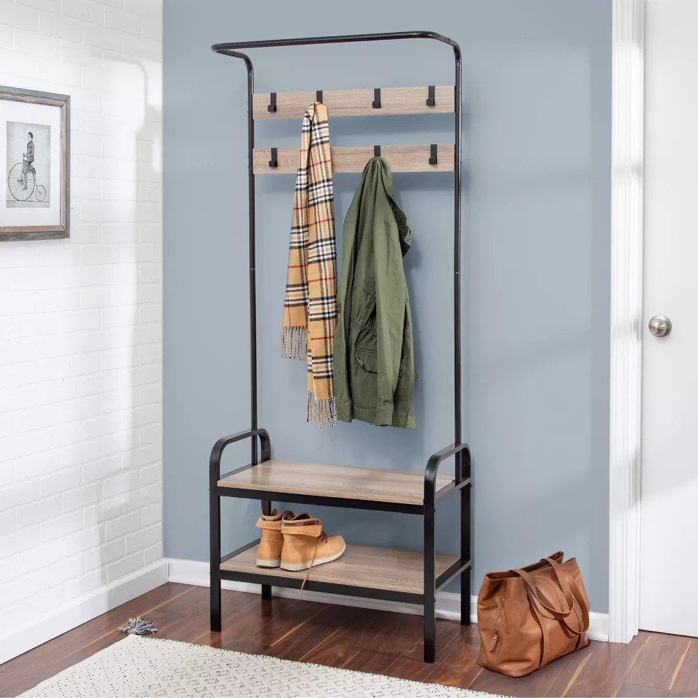 the storage bench with a scarf and a coat hanging from the hooks and boots on the bottom shelf