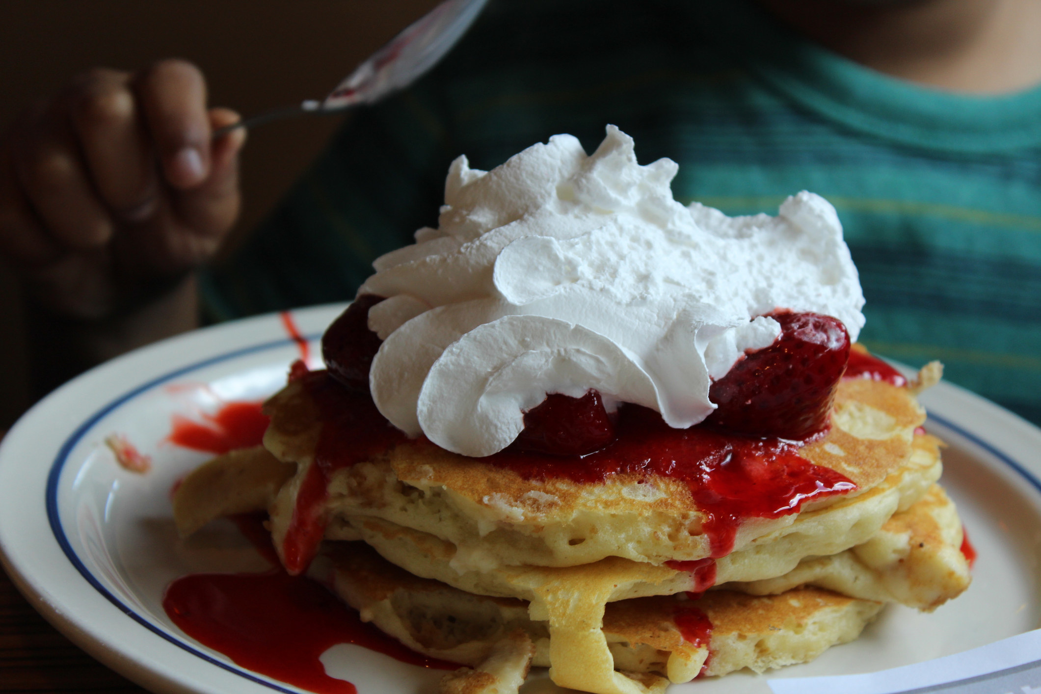 Pancakes topped with strawberries and whipped cream.