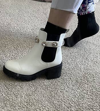 A reviewer wearing a white jeweled shoe