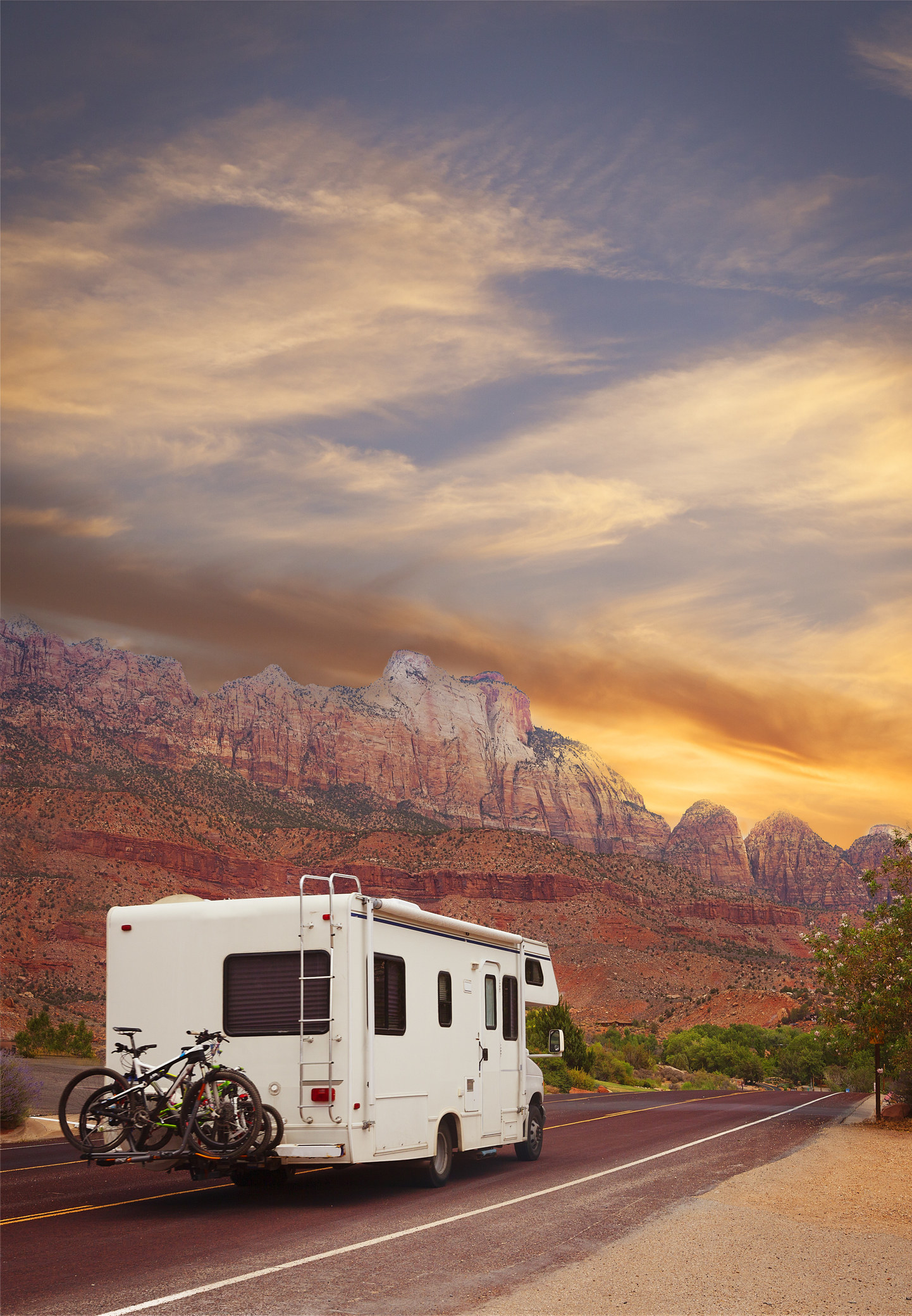 An RV driving into the sunset.