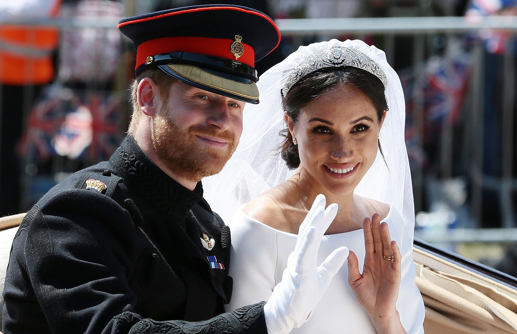 Prince Harry and Meghan waving to the crowd as they ride in a carriage after their wedding