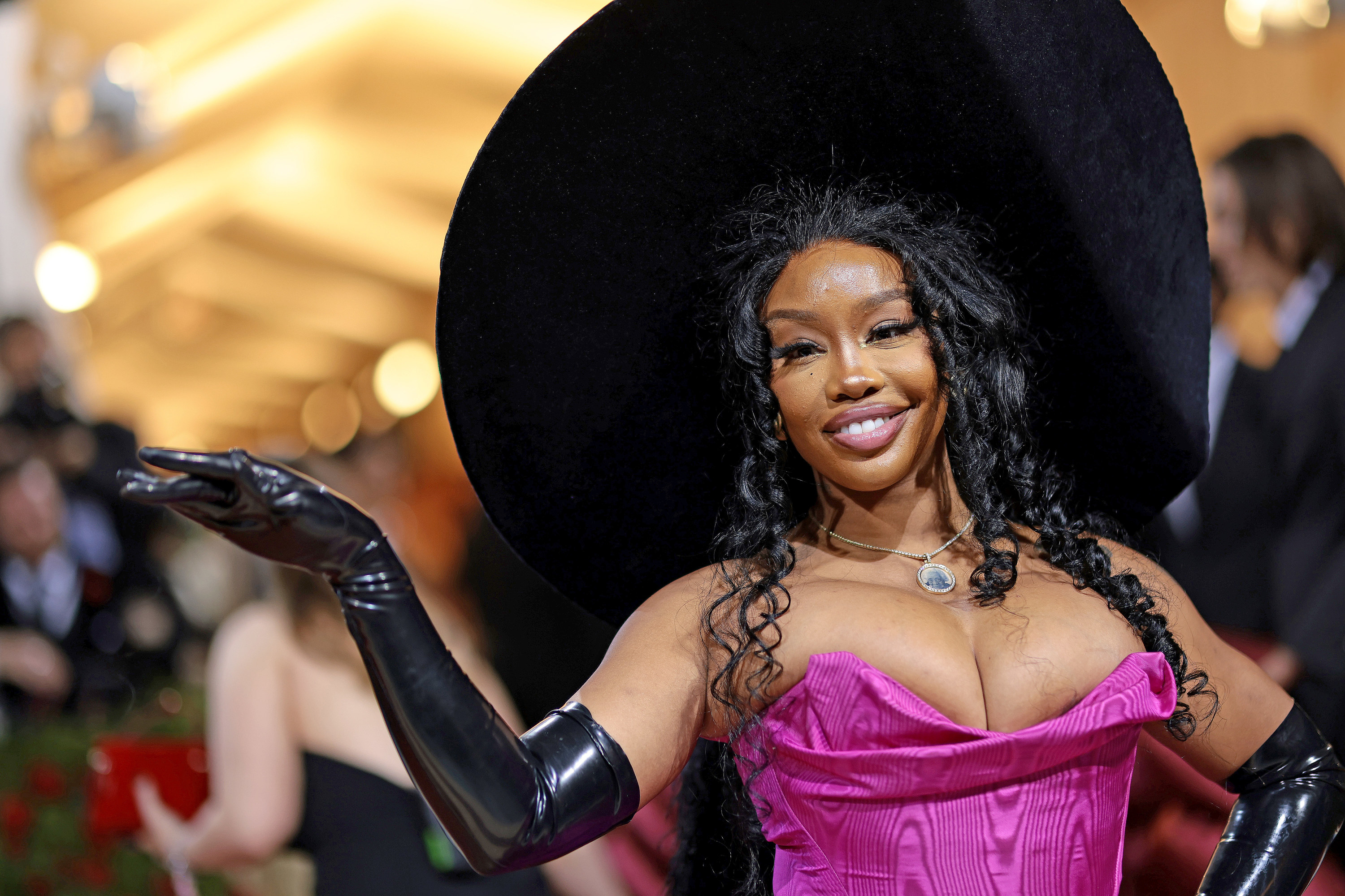 A close-up of SZA in a very wide-brimmed hat and long gloves