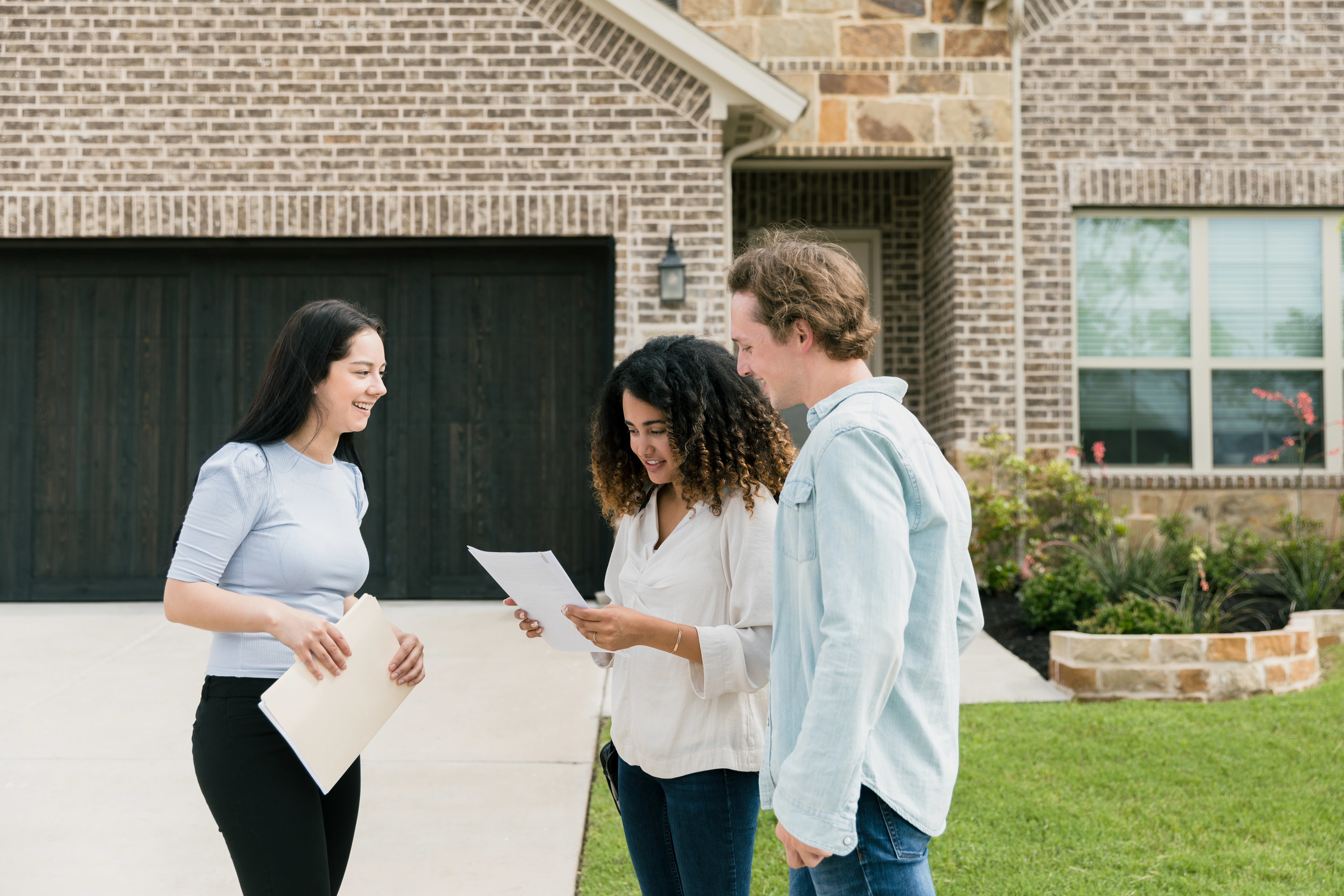 couple meeting with a realtor outside of a prospective home