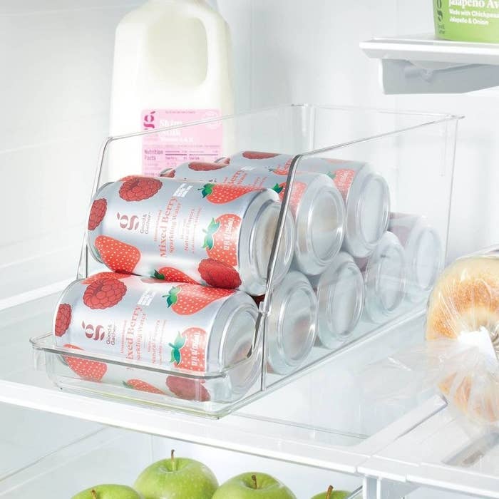 Cans of flavored sparkling h2o  are neatly organized successful  a wide   fridge bin adjacent  to a beverage  carton and apples