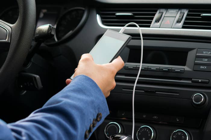 A person holding a cellphone attached to a car charger