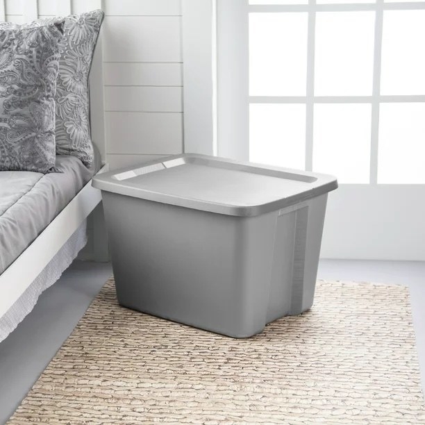 a gray storage box next to a bed