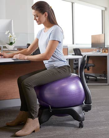 a model sitting on the purple exercise ball chair