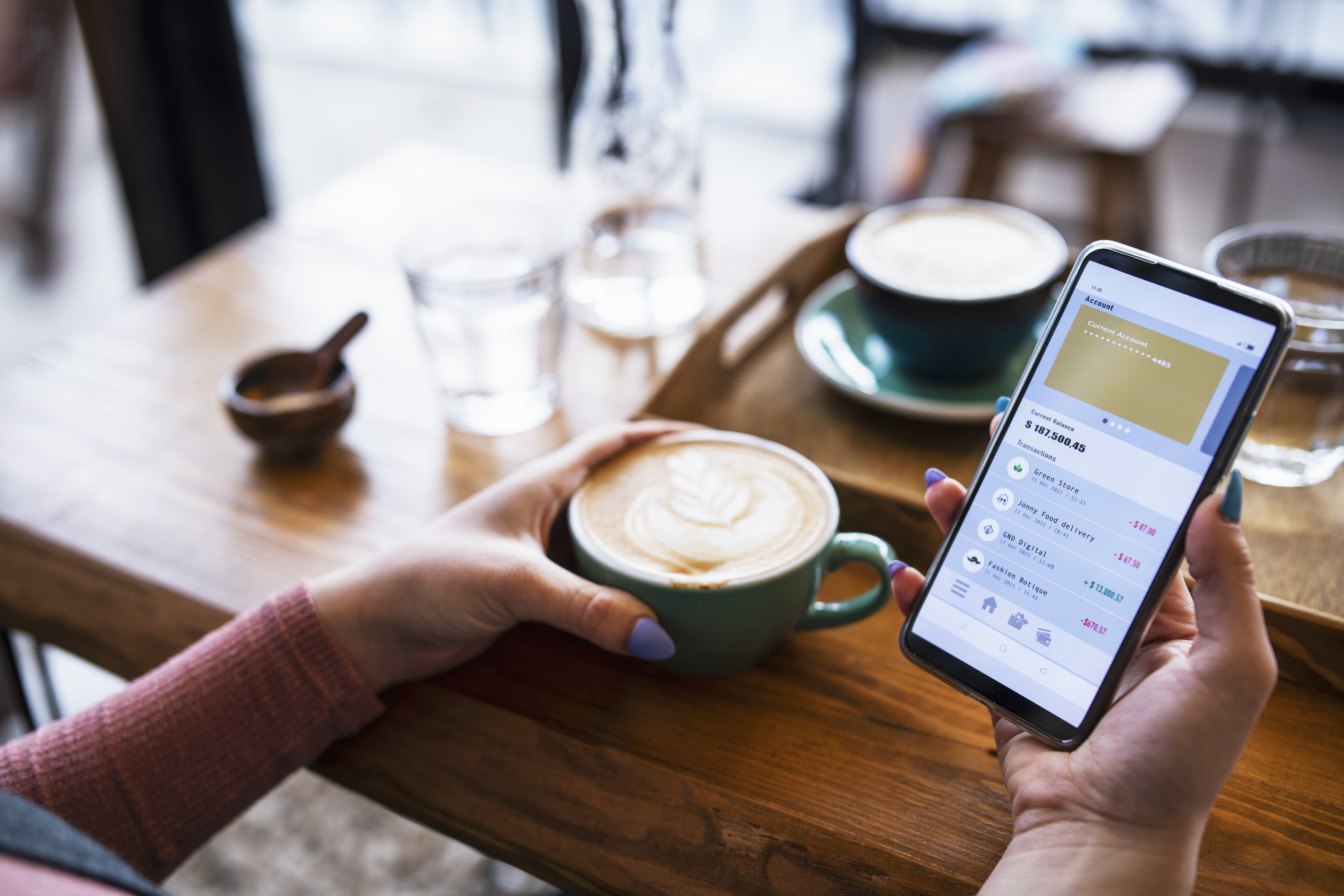 a person drinking coffee and looking at their bank