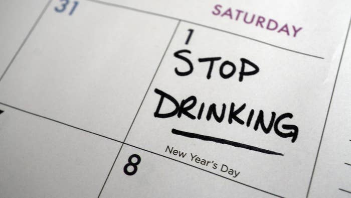 A closeup of a calendar with "STOP DRINKING" written on New Year's Day