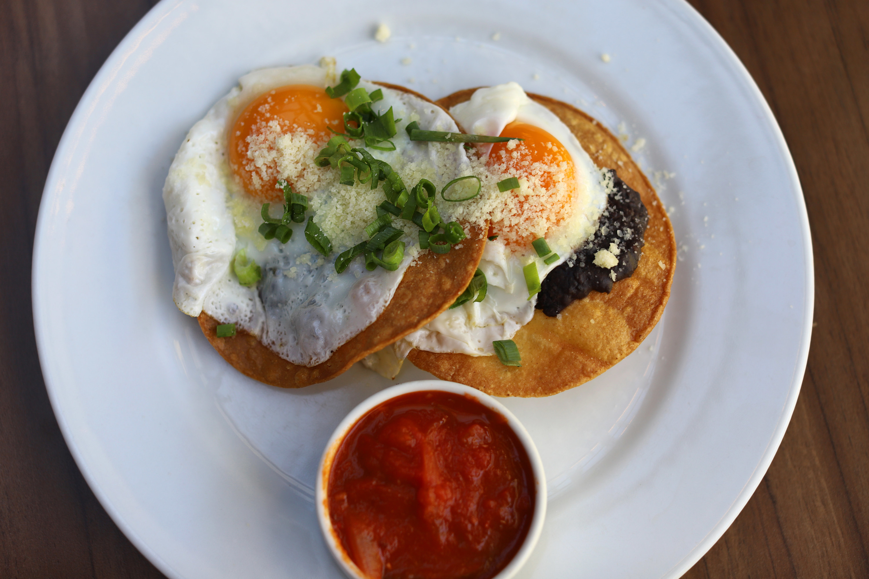 eggs on top of tortillas on a plate with a side of salsa