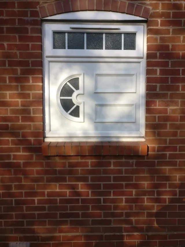 a strange door window combination set in a brick wall