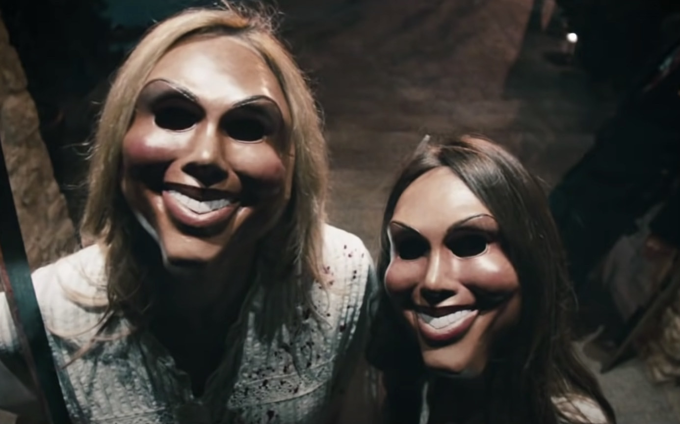 Two women wearing scary purge masks