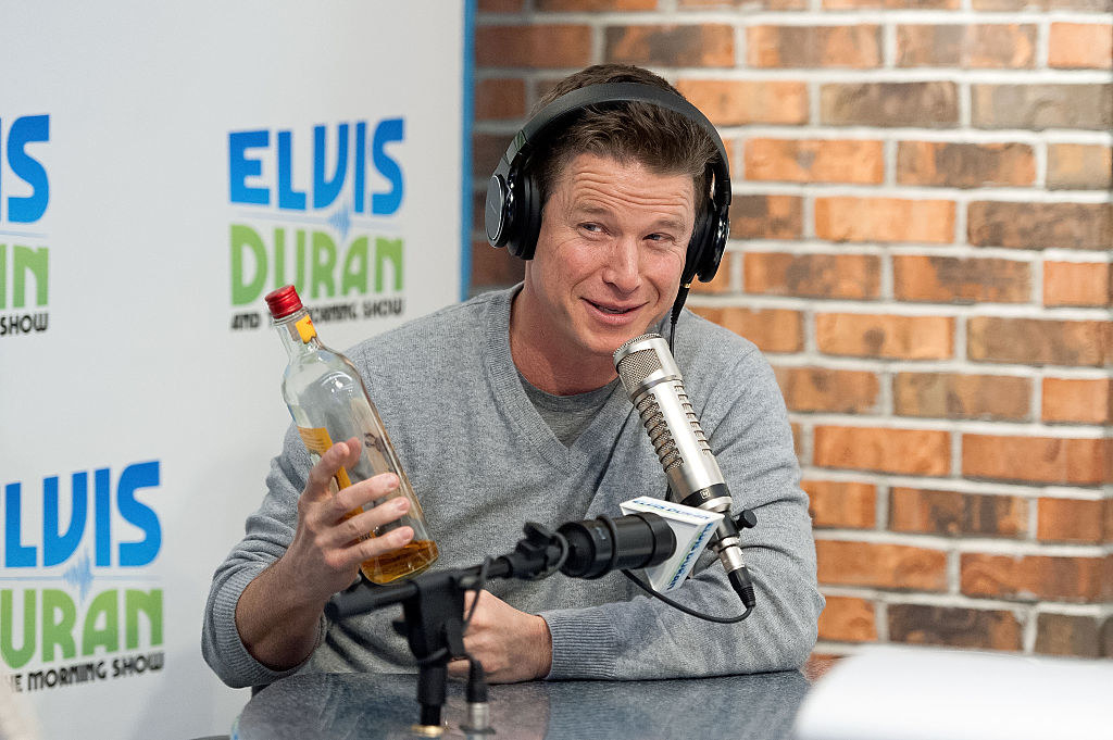 billy talking into a mic while holding a bottle of liquor
