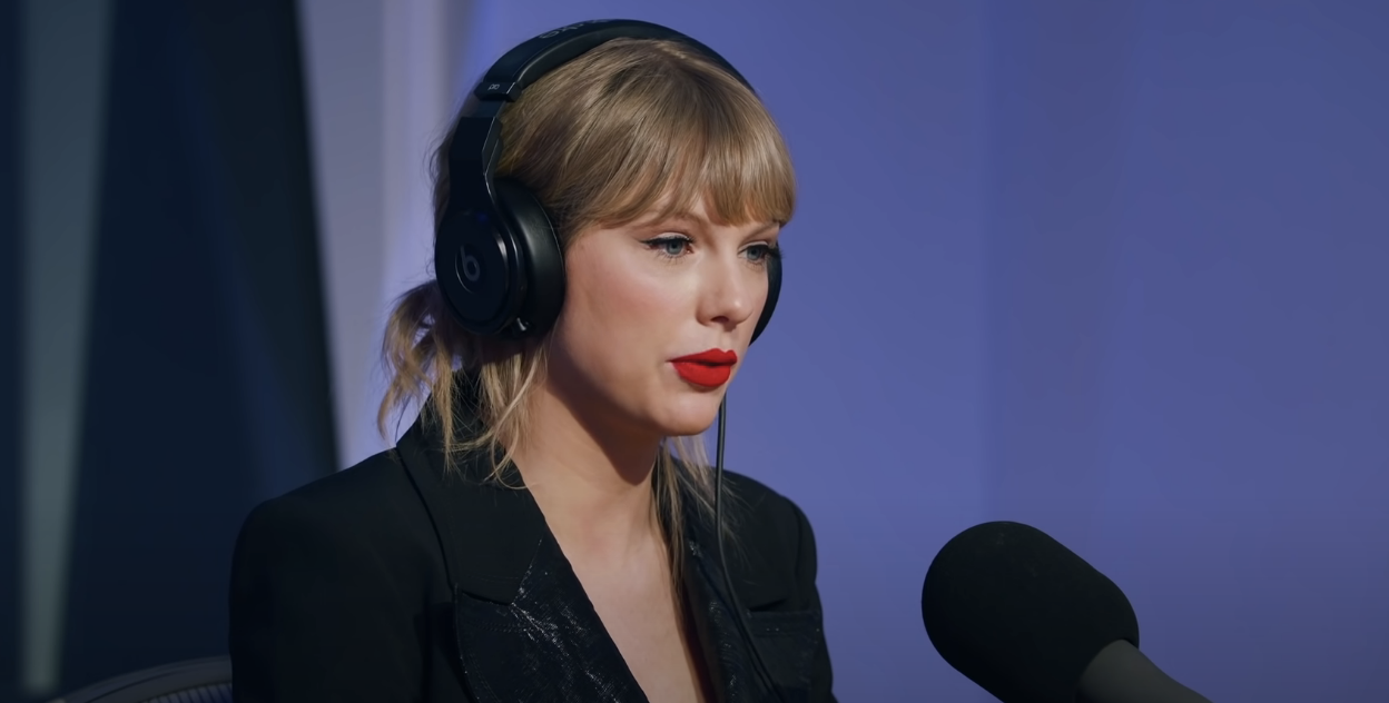 closeup of taylor doing her interview with a mic in front of her and headphones on