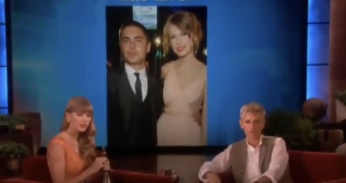 ellen and taylor sitting with a photo of taylor and zac ephron blown up on a screen behind them