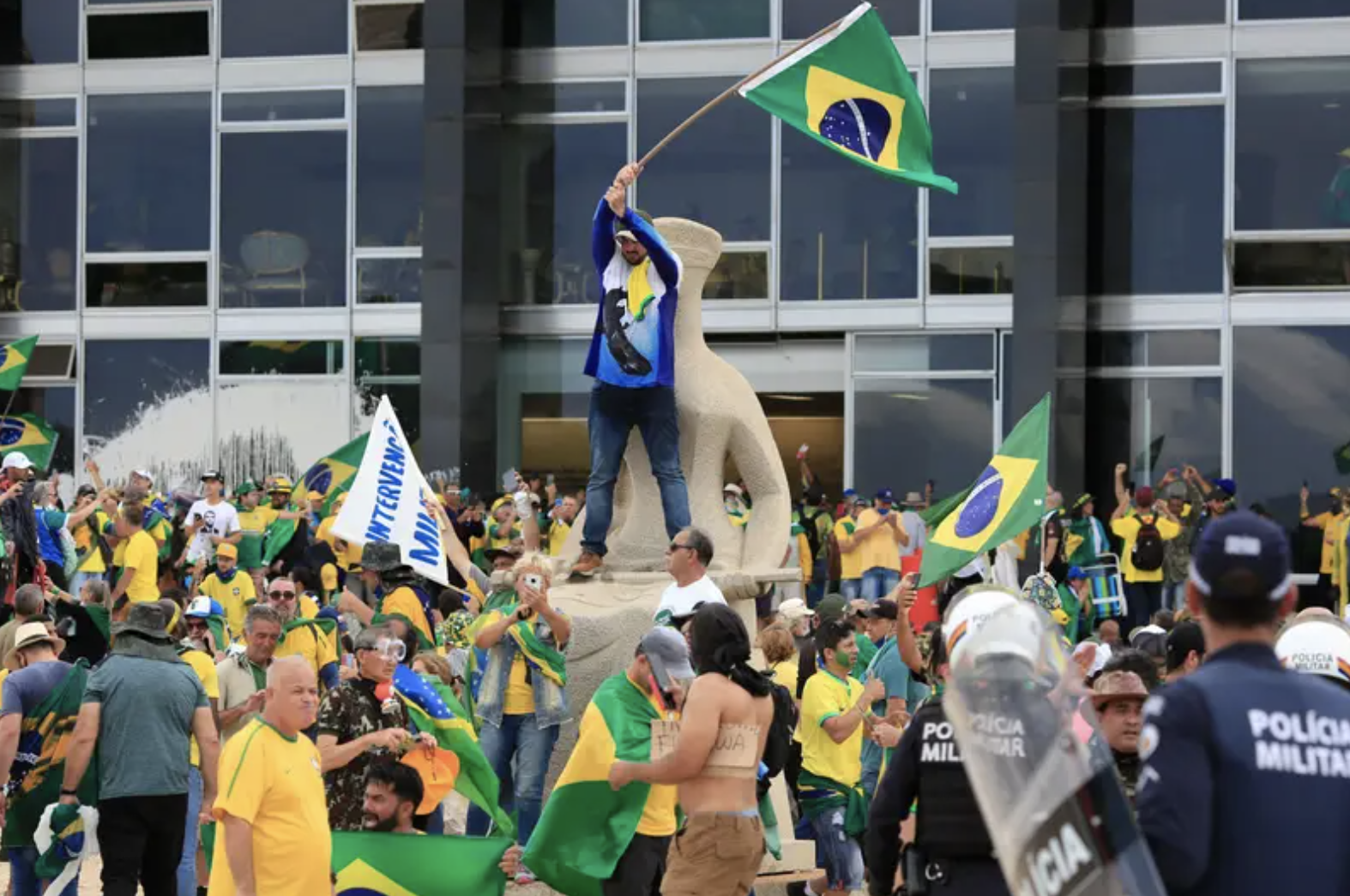 a crowd of protesters in brazilian flag colors storm the presidential palace in Brasília