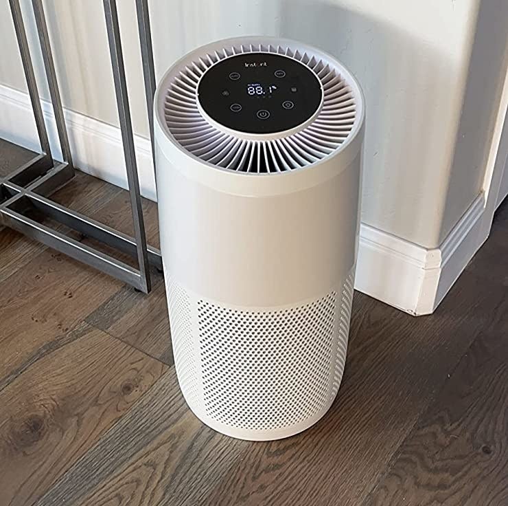 Reviewer&#x27;s white air purifier on hardwood floor of room