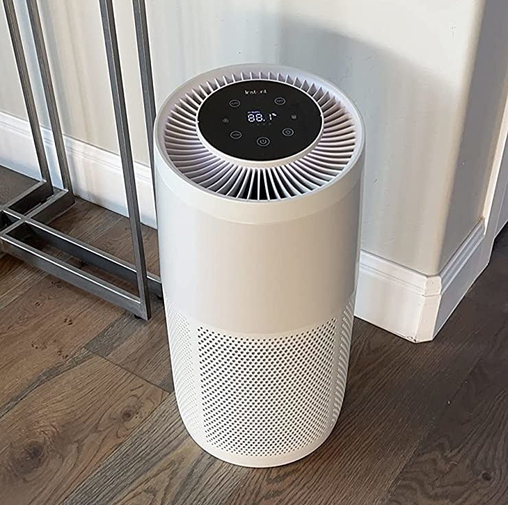 Reviewer&#x27;s white air purifier on hardwood floor of room