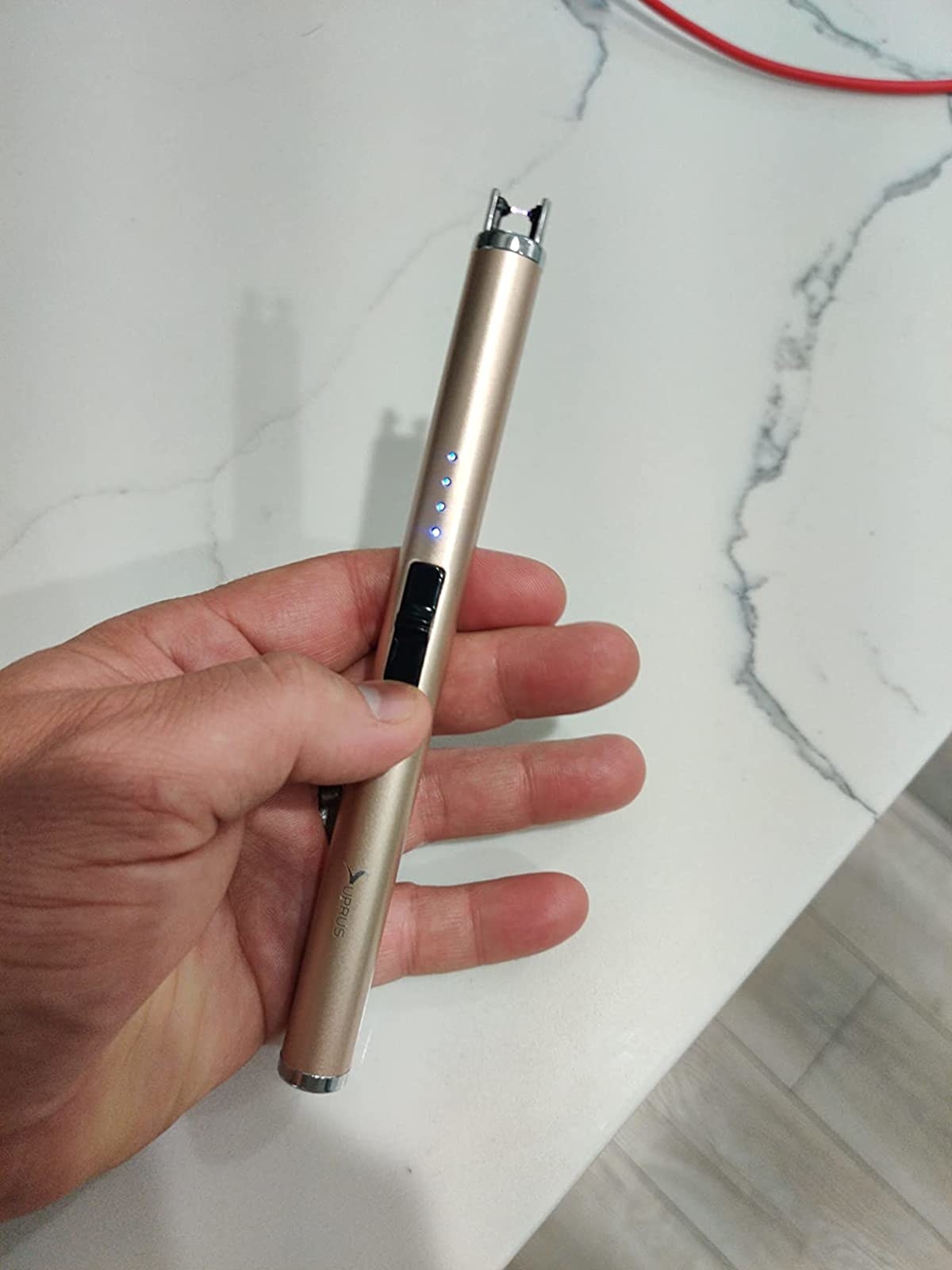 a reviewer holding a rechargeable lighter in gold