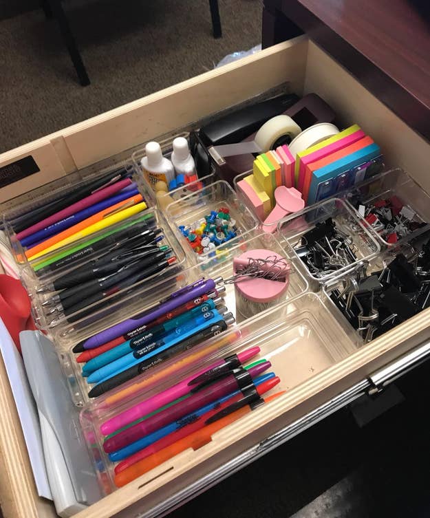 reviewer's desk drawer with a variety of clear bins inside organizing various small office items