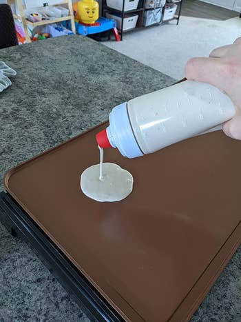 Reviewer pouring the batter from the bottle onto a griddle
