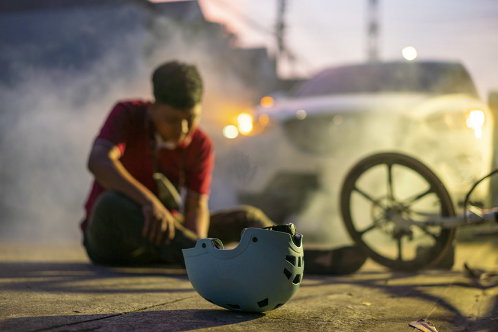 A boy on the ground next to an accident