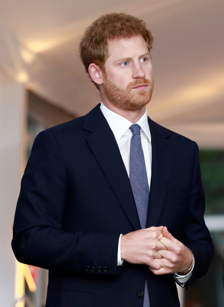 Harry wears a suit and tie as he looks on at an event