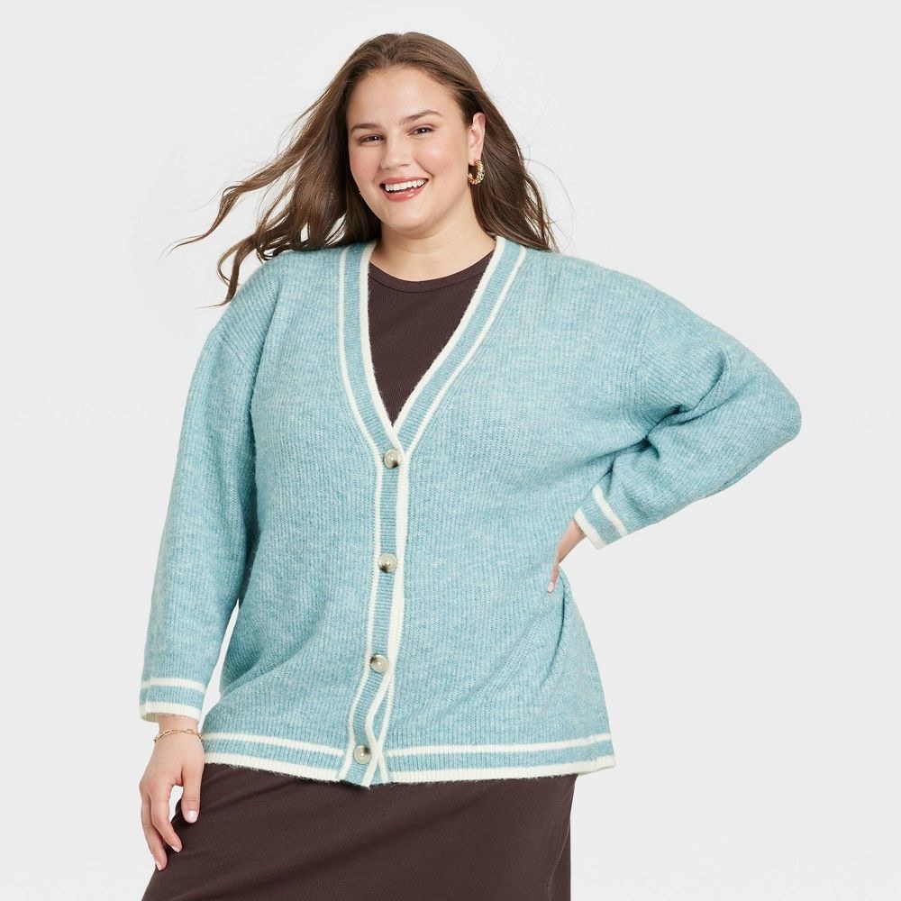 model in light blue button-front cardigan with cream stripes around the trim