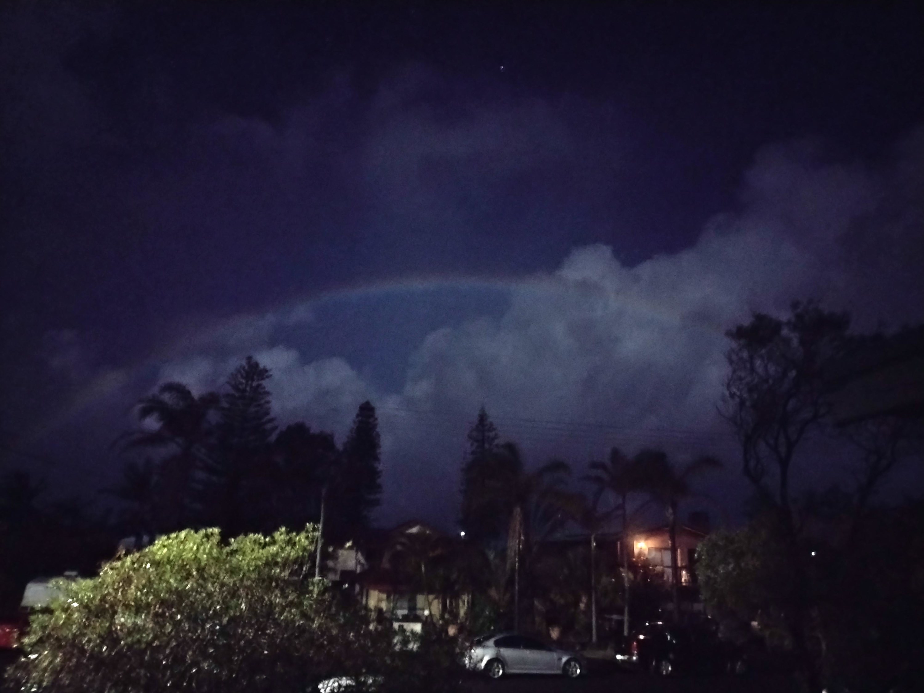 A rainbow behind clouds at night
