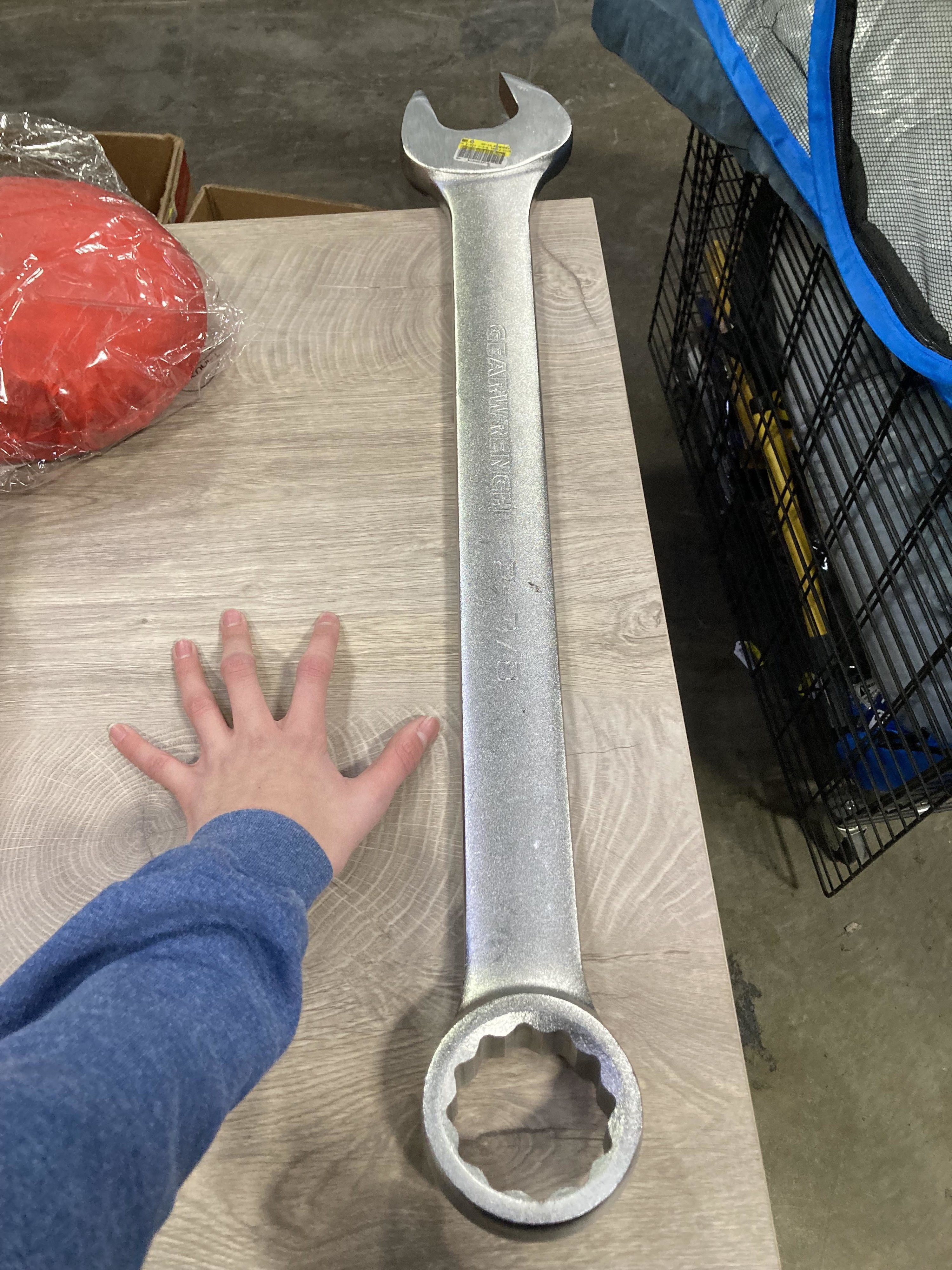 A giant wrench about twice as long as a person&#x27;s arm next to it