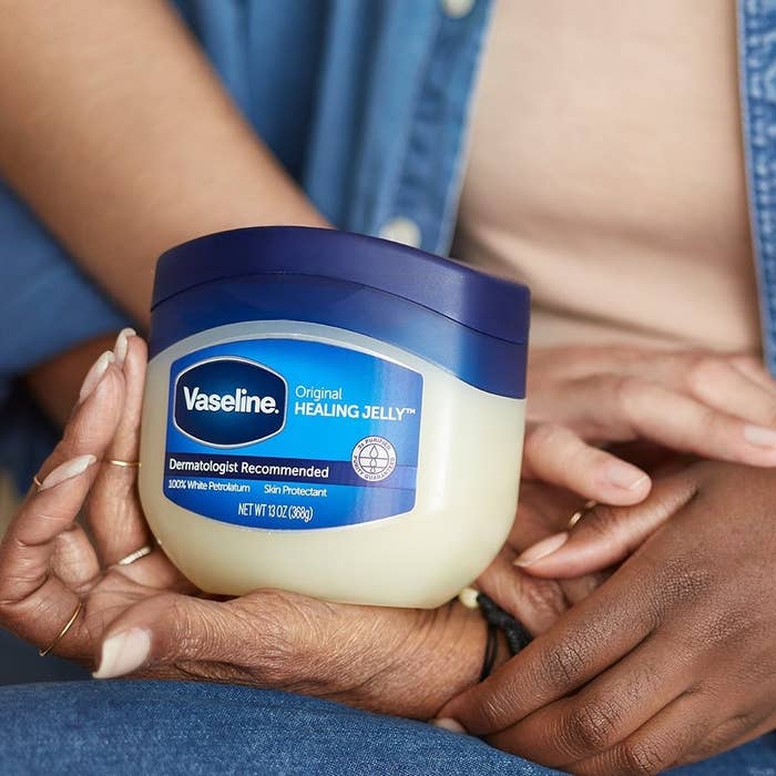 a person holding a tub of vaseline