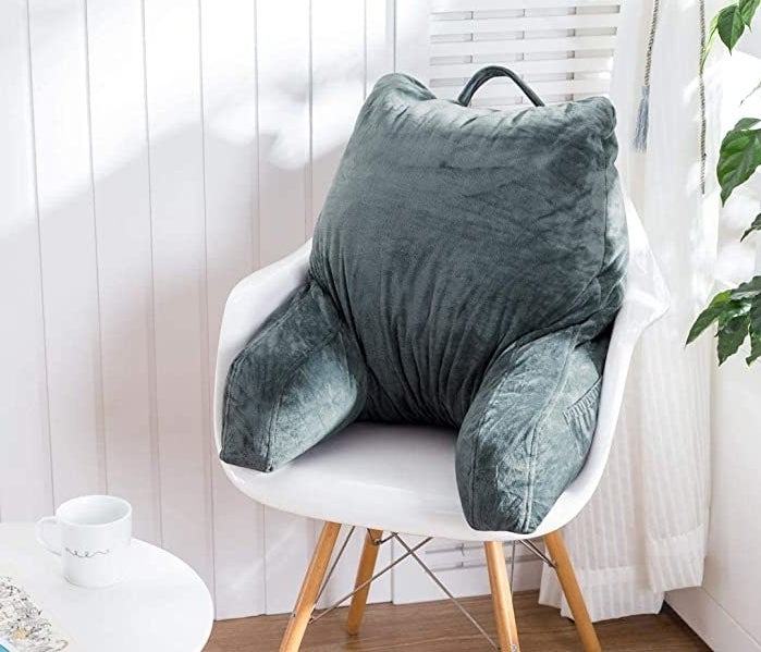 a reading pillow on a chair in a bright room