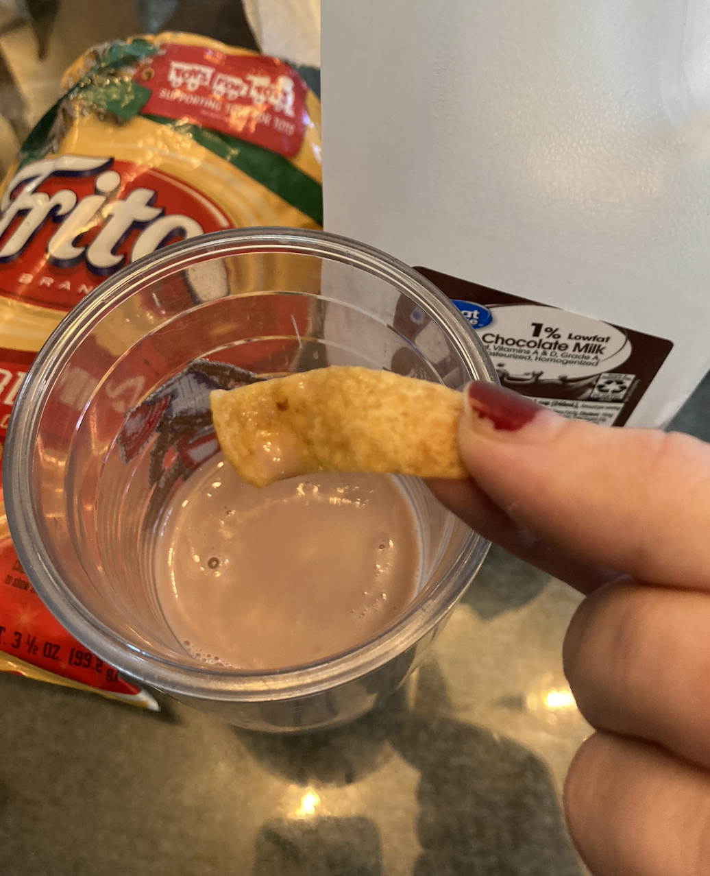 fritos being dipped in a glass of chocolate milk