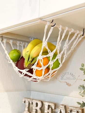 The macrame net hung below a cabinet with wood dowels and hooks