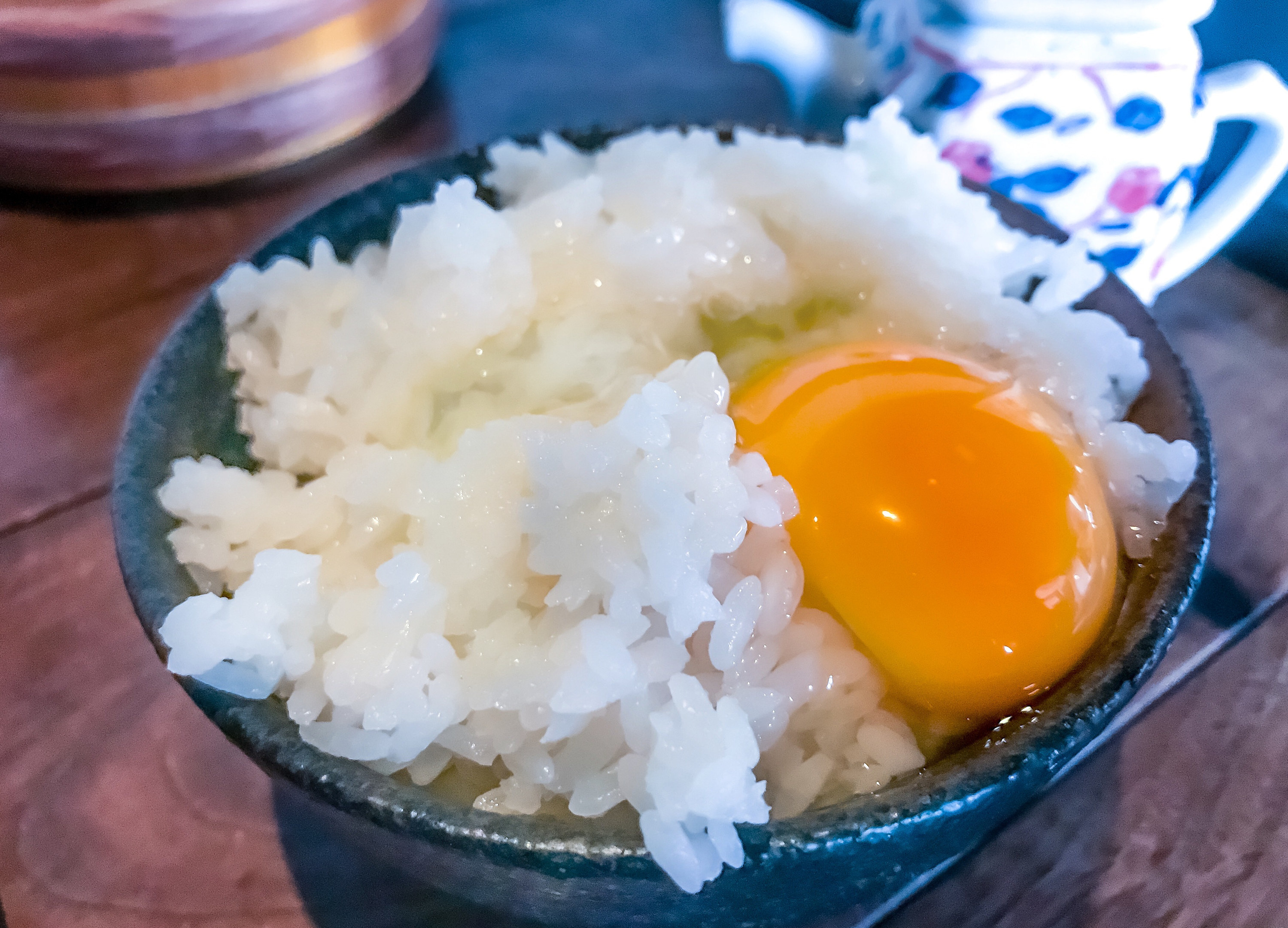 A cracked egg over a bowl of white rice