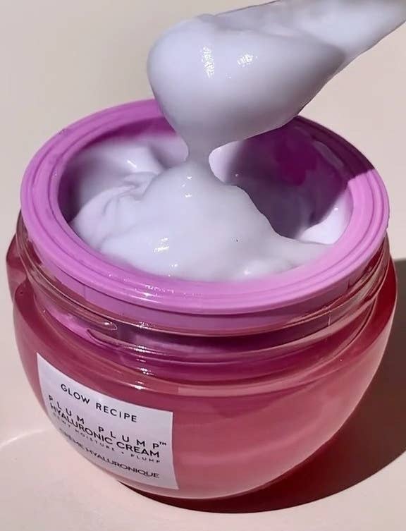 a jar of the moisturizer open and someone scooping some out