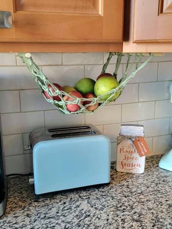 buzzfeed editor's green basket hanging underneath a cabinet
