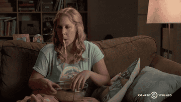 Amy Schumer eating spaghetti on the couch