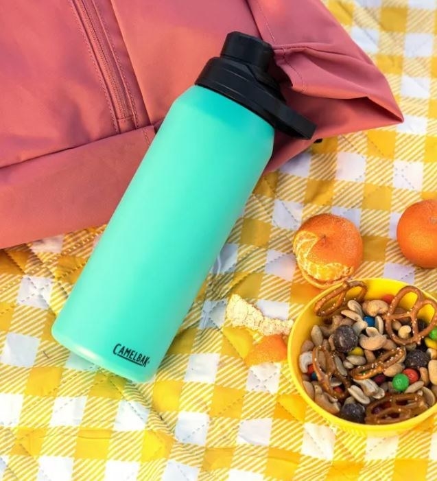 Mint blue reusable water bottle on a picnic blanket