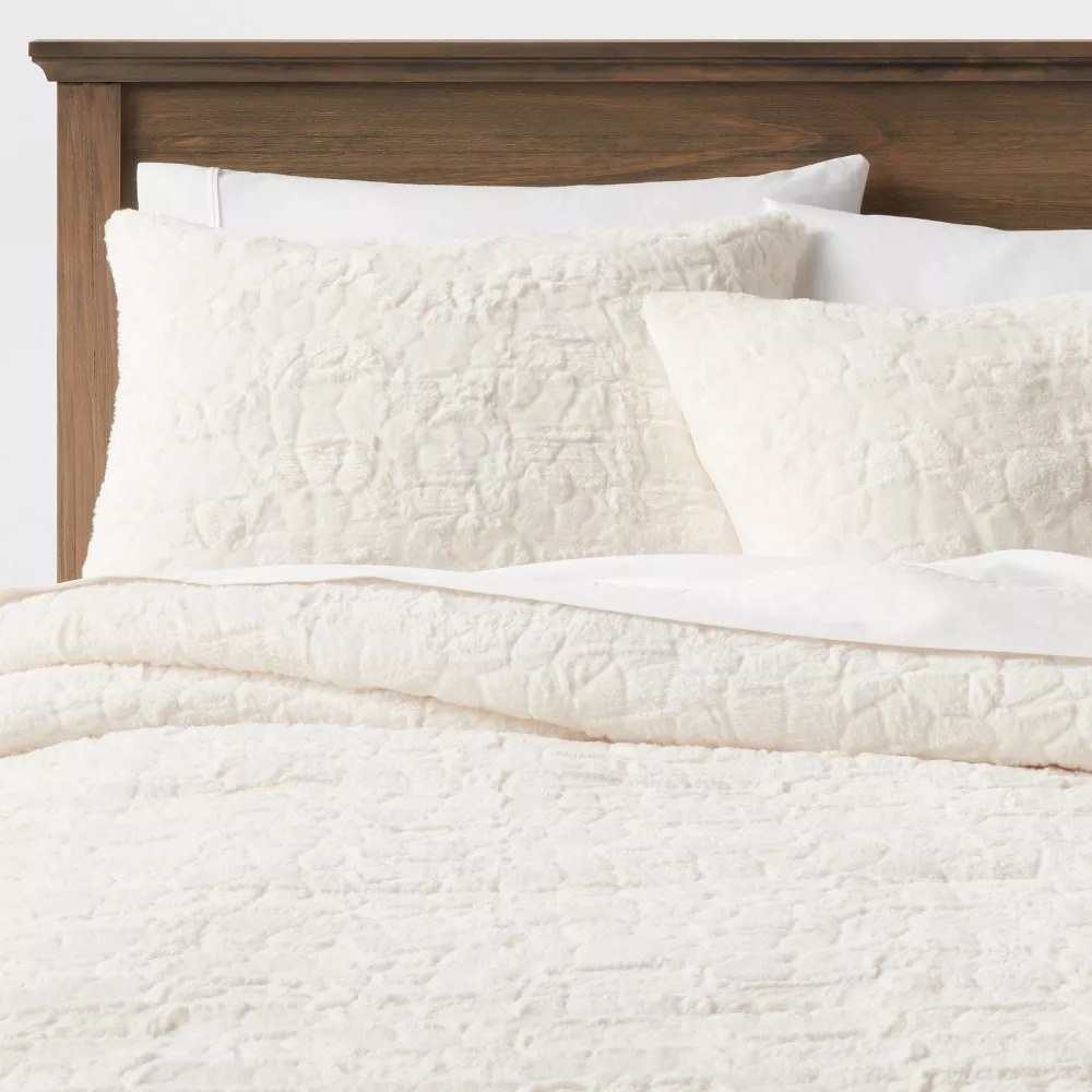 The cream-colored comforter and two matching shams on a bed
