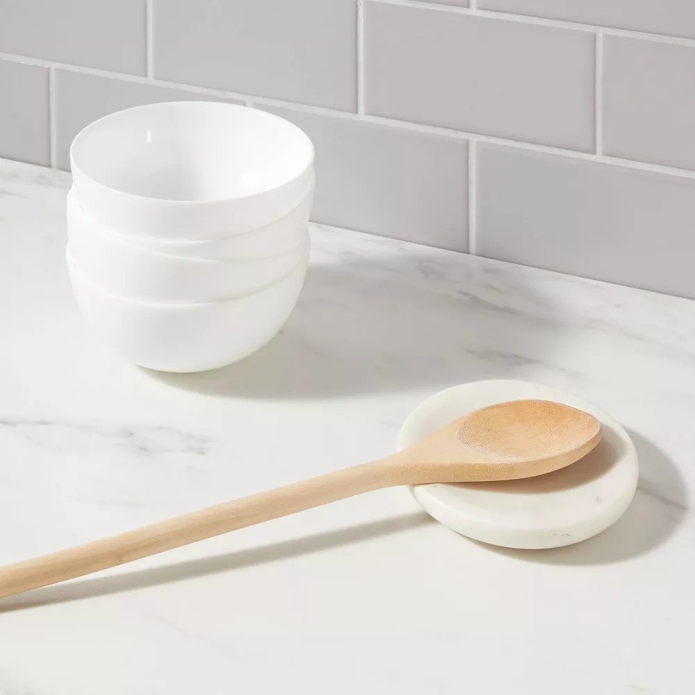 A wooden spoon on top of the circular spoon rest