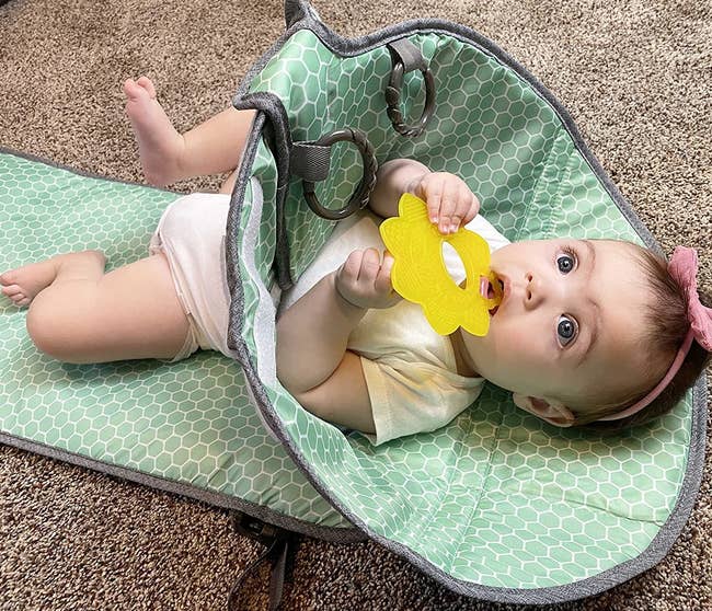 A baby model lying in the mint green diaper mat with a cone barrier