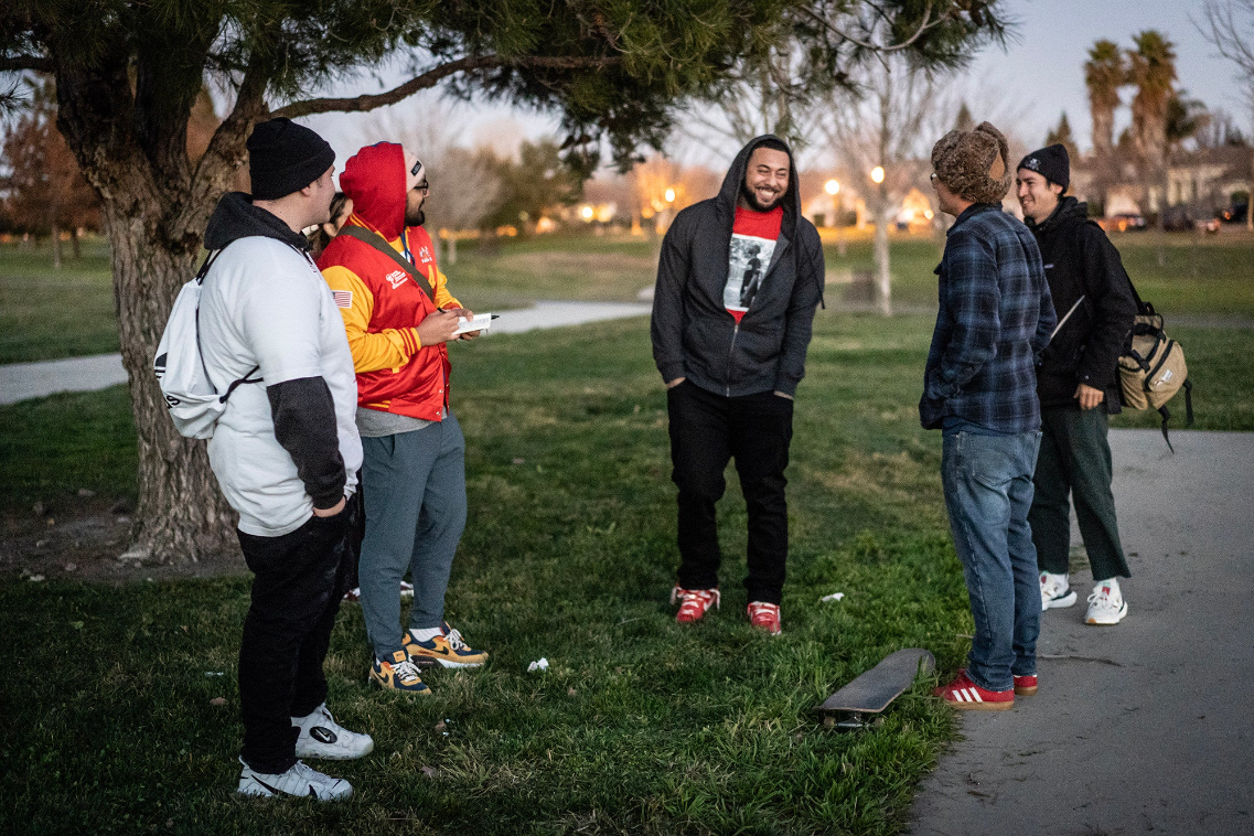 a group of young adult male friends gather in a circle at a park