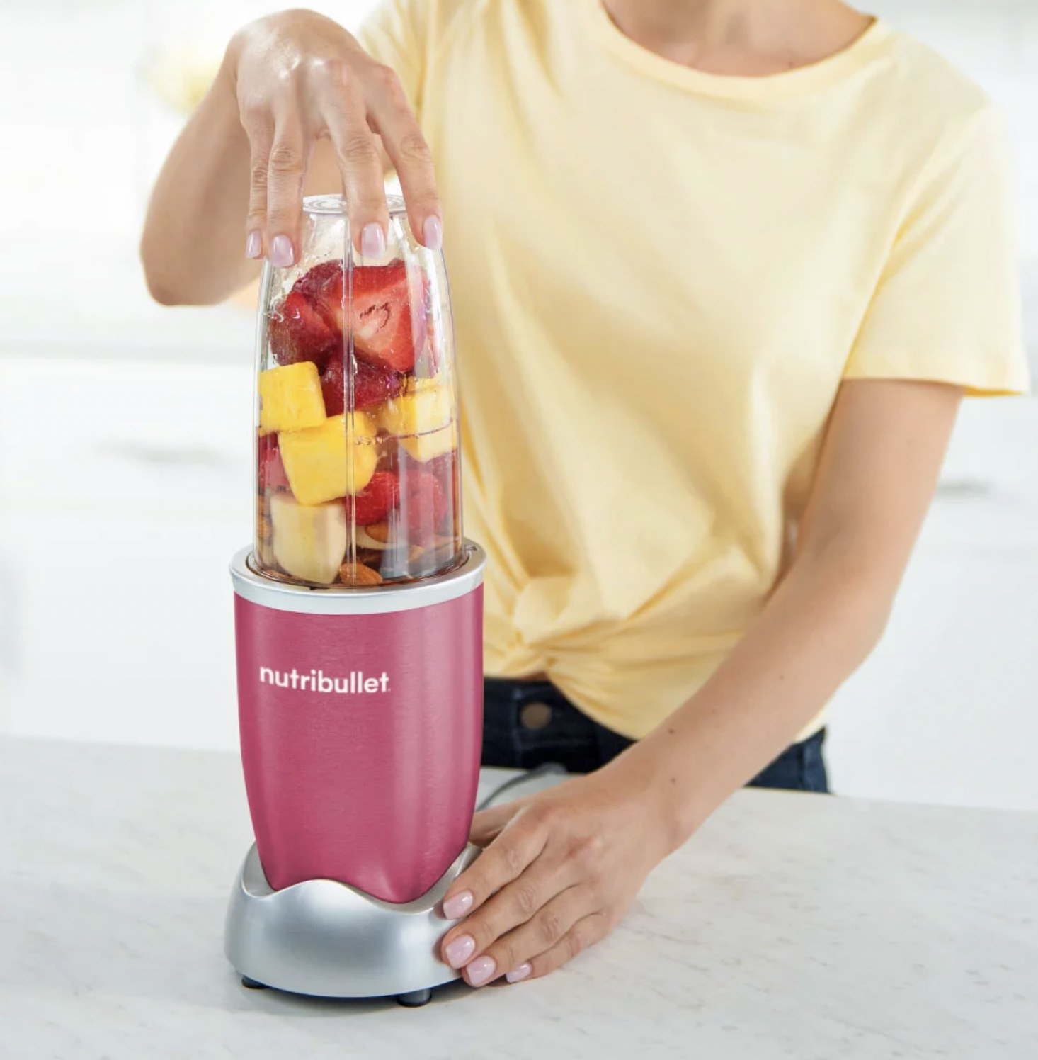 Someone mixing fruit in the pink blender