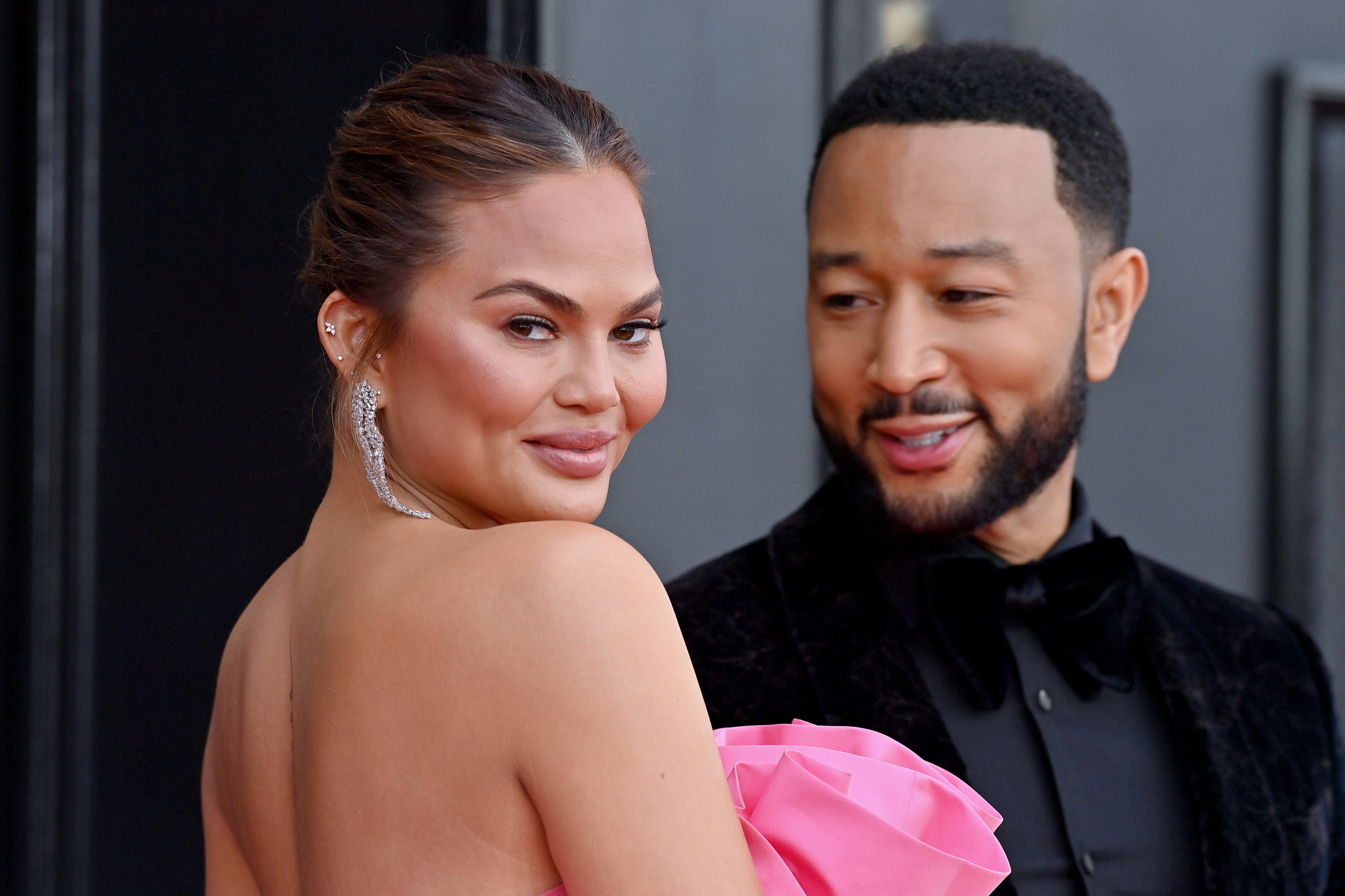 John looks at Chrissy as she looks over her shoulder at a red carpet event