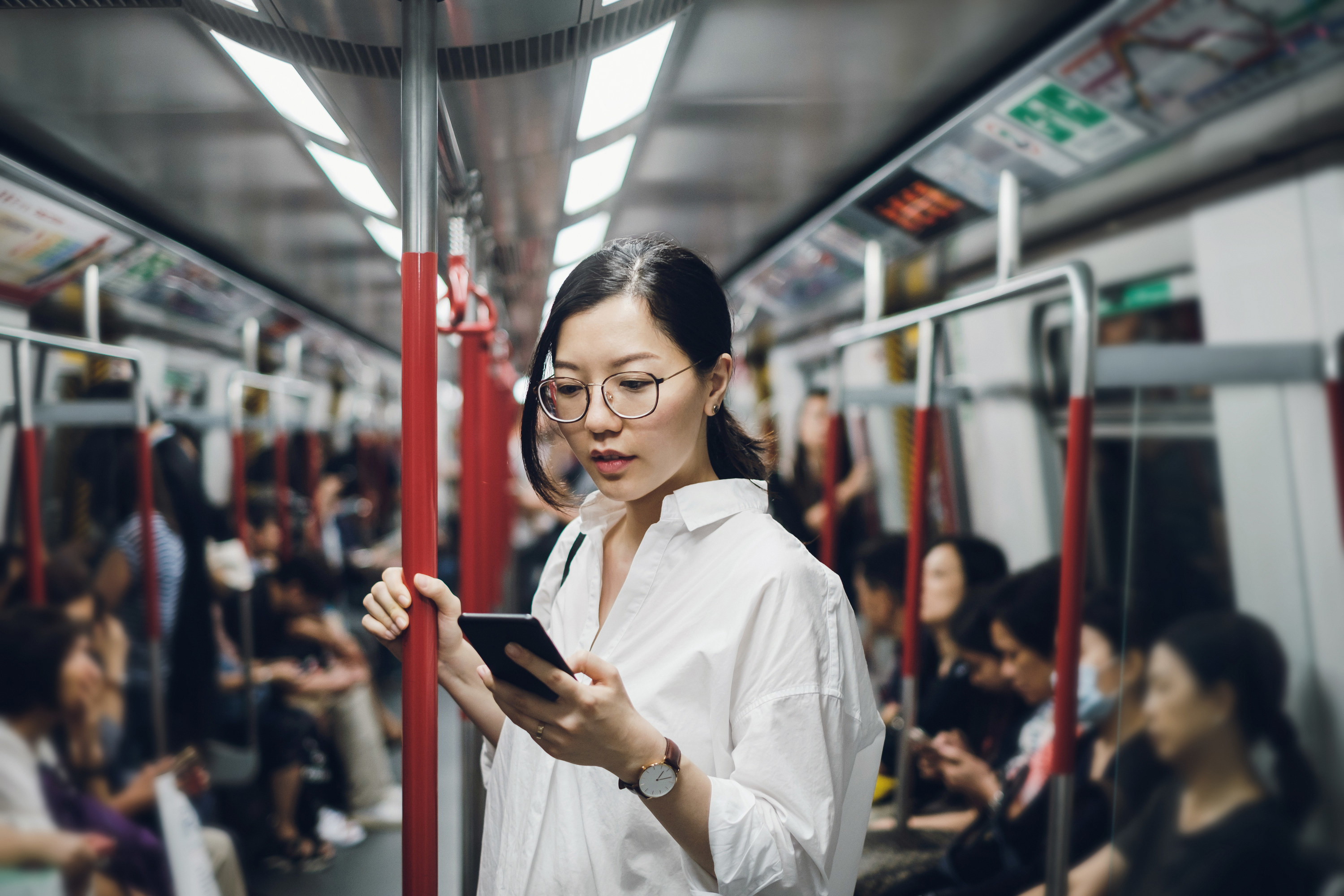 a woman looking on her phone while on the subway