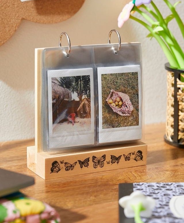 a wooden photo album stand with a butterfly pattern along the bottom