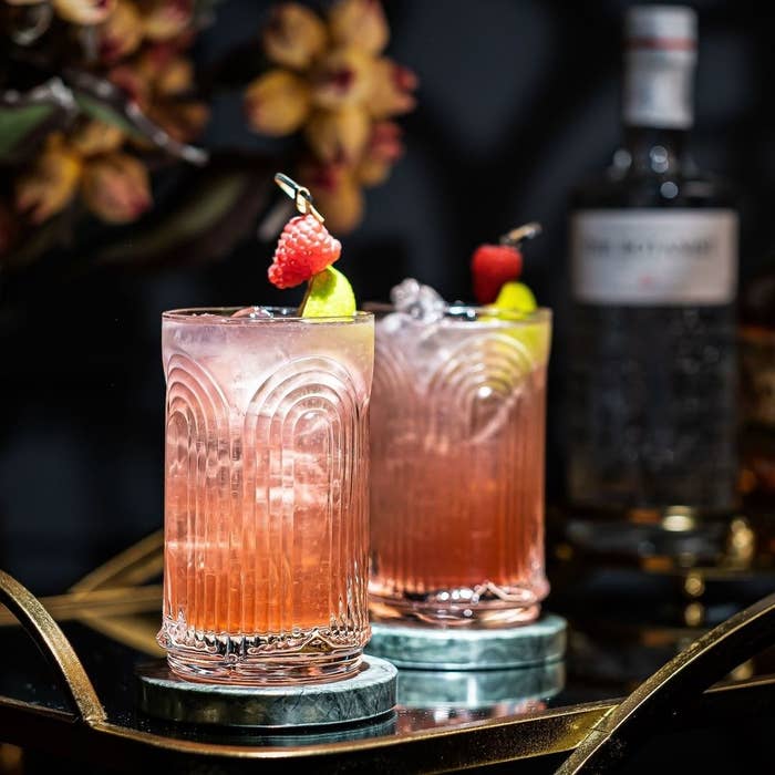 Two glasses on a gold bar cart filled with cocktails