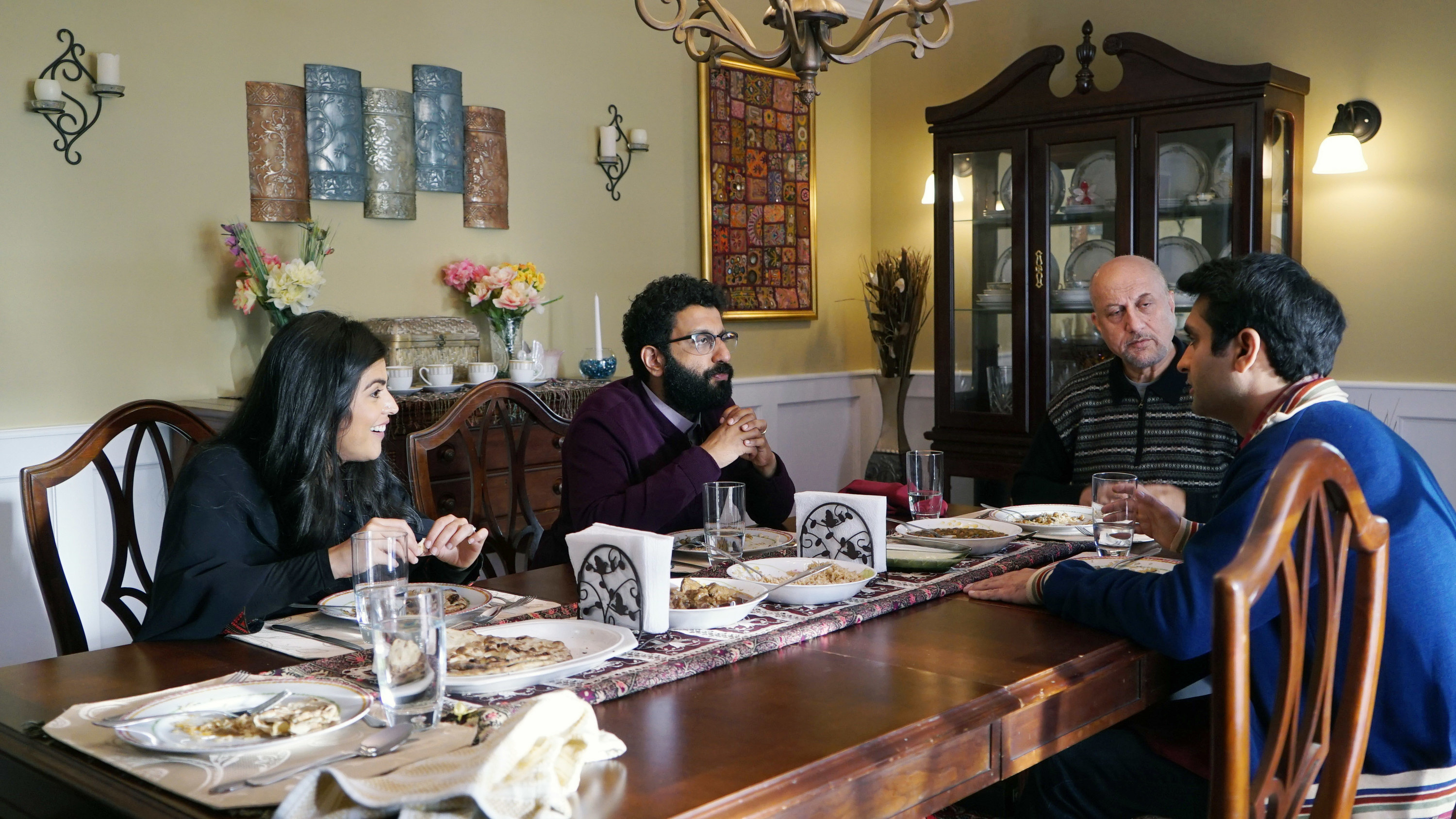Kumail, his father, and others seated around a table