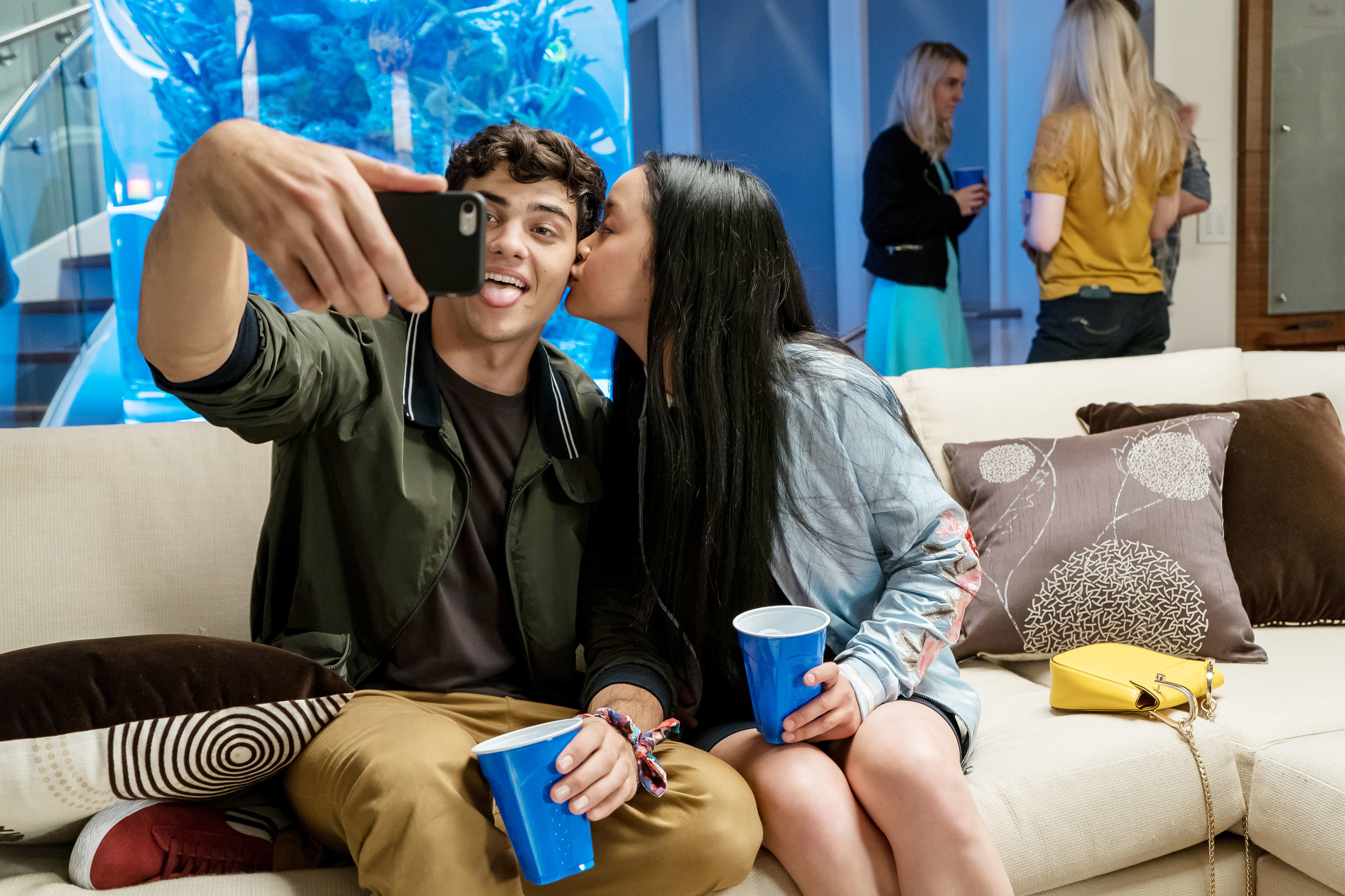 Peter and Lara Jean taking a selfie while sitting on a couch